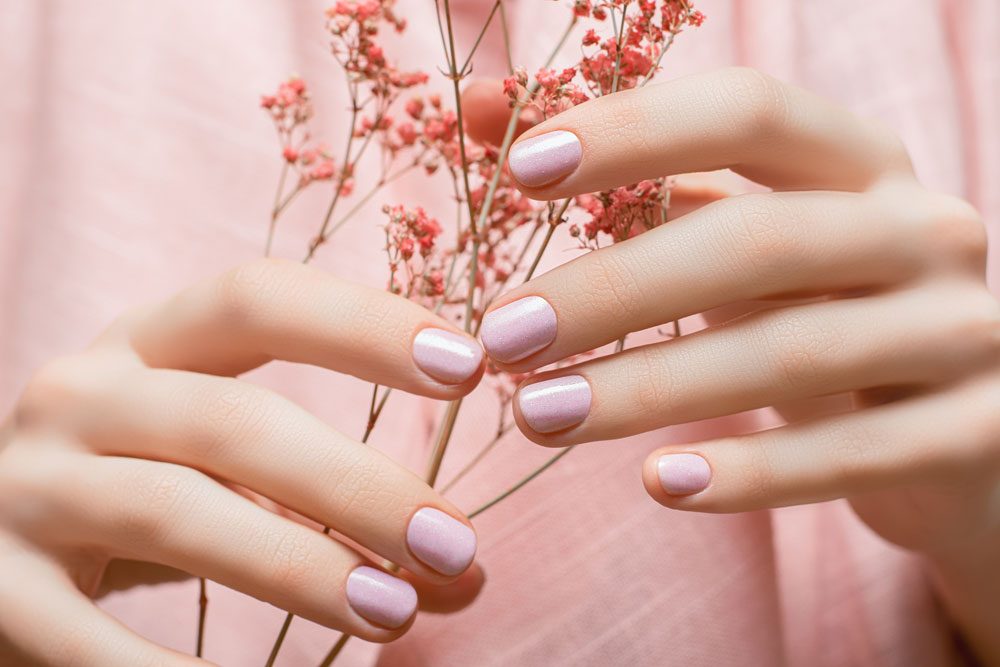 Frau mit pastellfarbenem Nagellack.