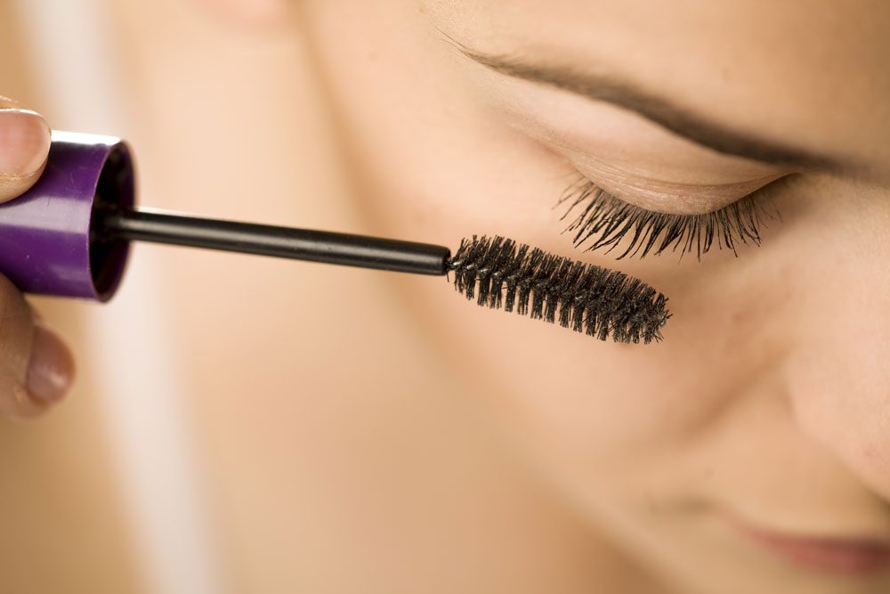 Frau schminkt sich Wimpern mit Mascara.