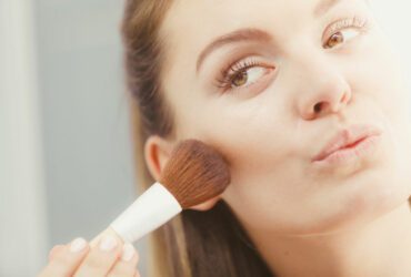 Frau trägt Bronzer auf.