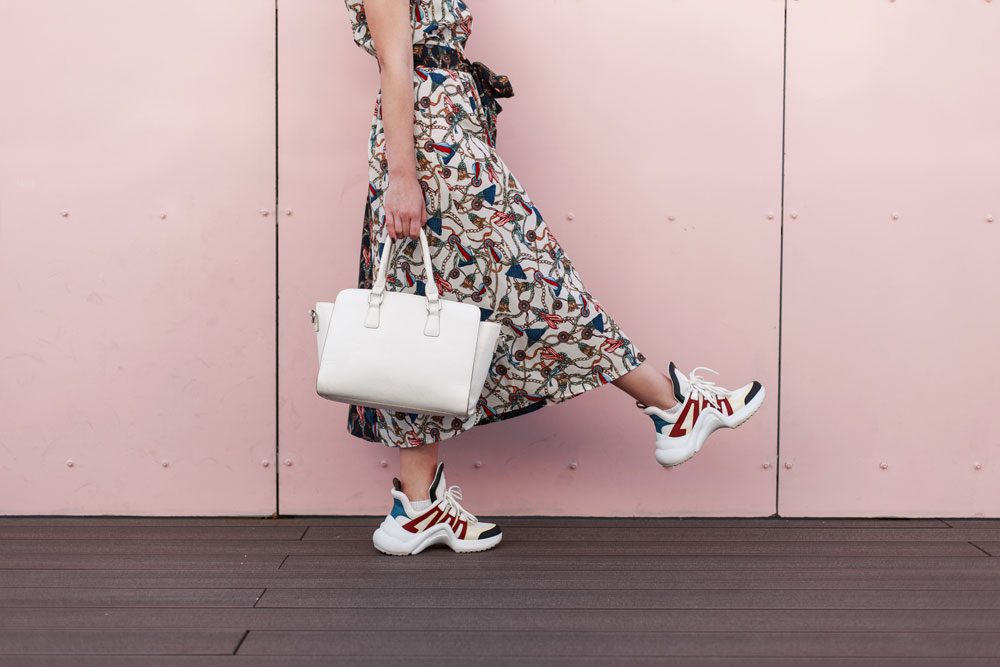 Kleid und Turnschuhe Frau trägt Turnschuhe zum Kleid.