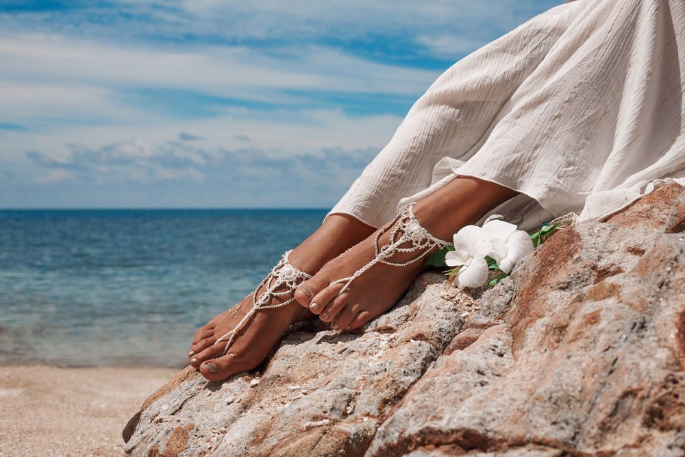 Schmuck an den Füßen einer Braut am Strand