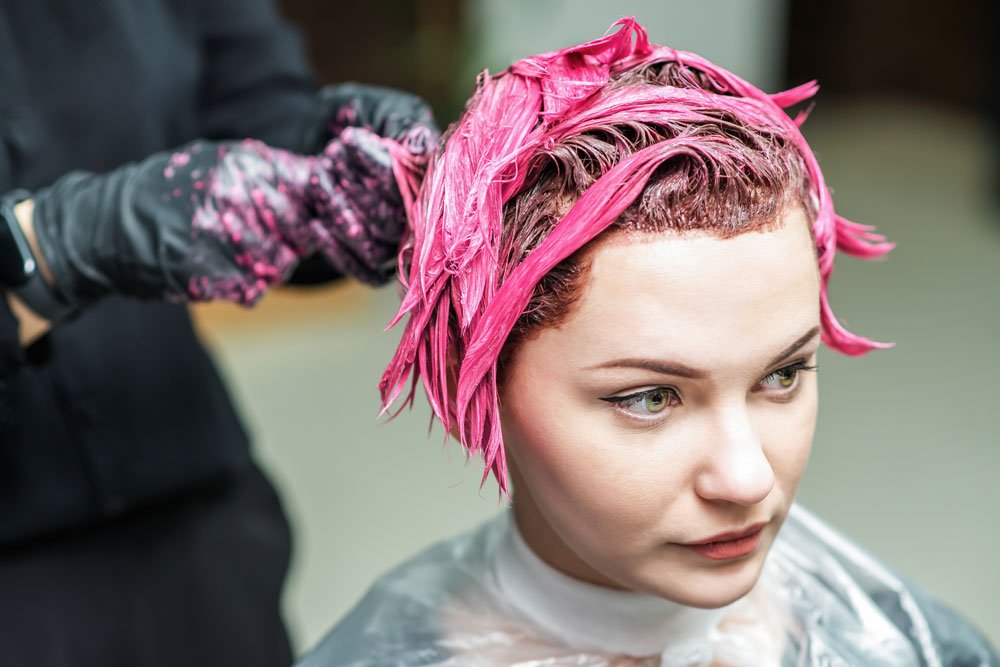 Frau bekommt die Haare rosa gefärbt