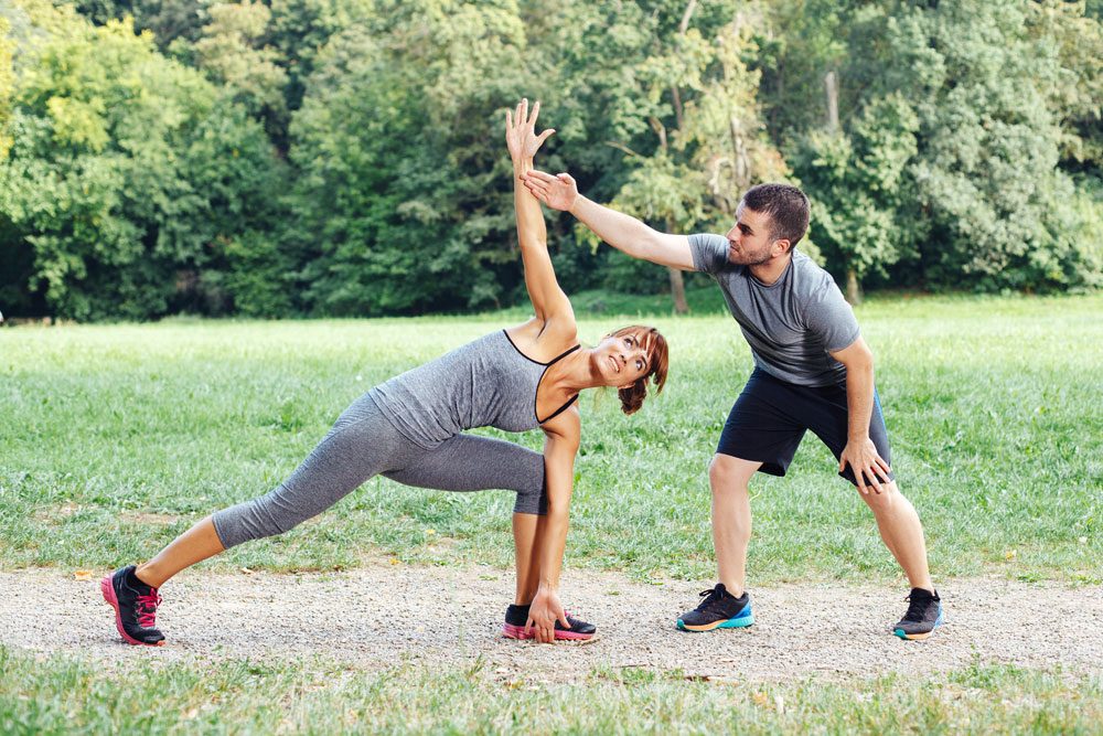 Personal Trainer mit Frau im Park.