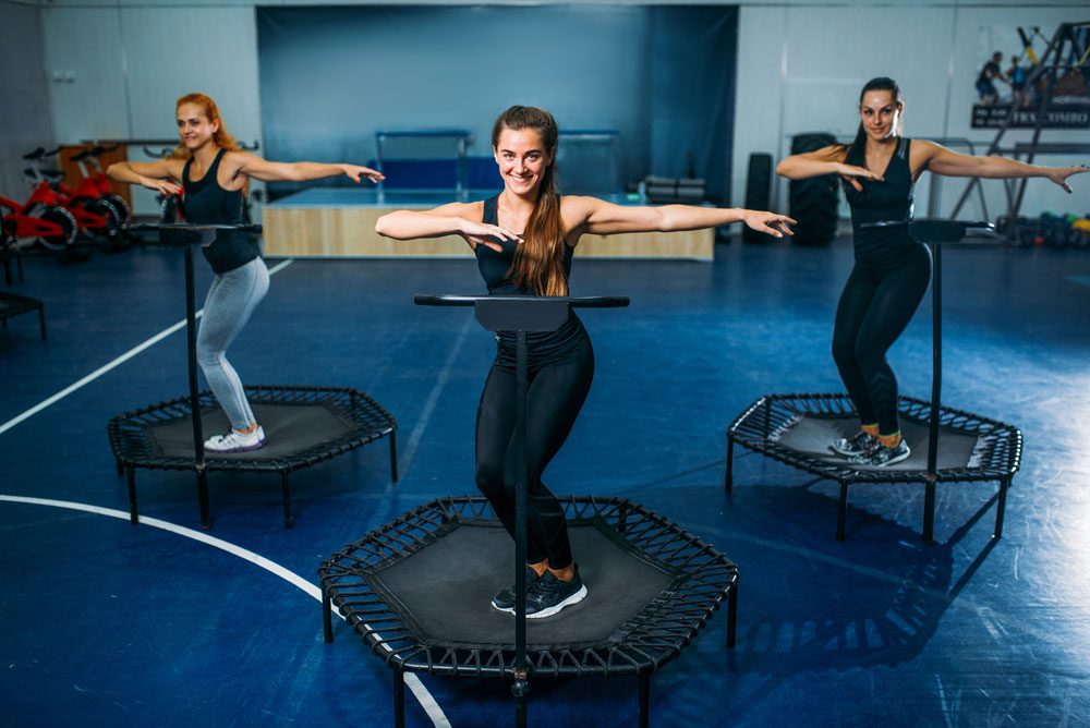 Frauen auf dem Fitness-Trampolin Twist-Übung auf dem Trampolin