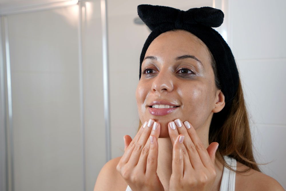 Oil cleansing Frau schminkt sich mit Öl ab.